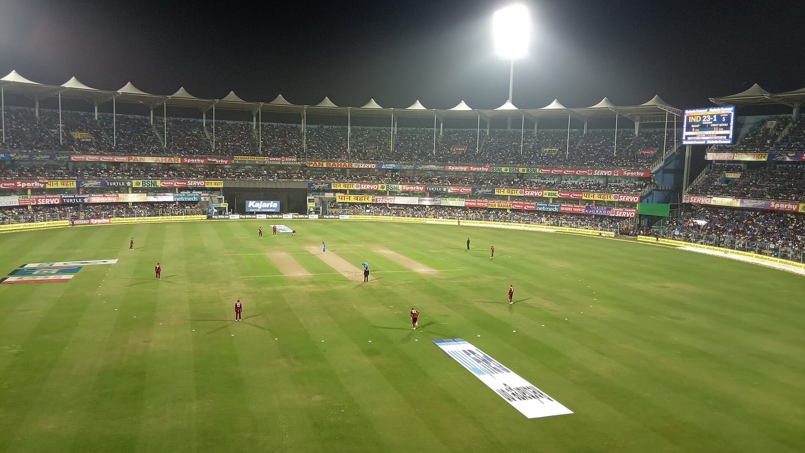 A cricket match under floodlights at night